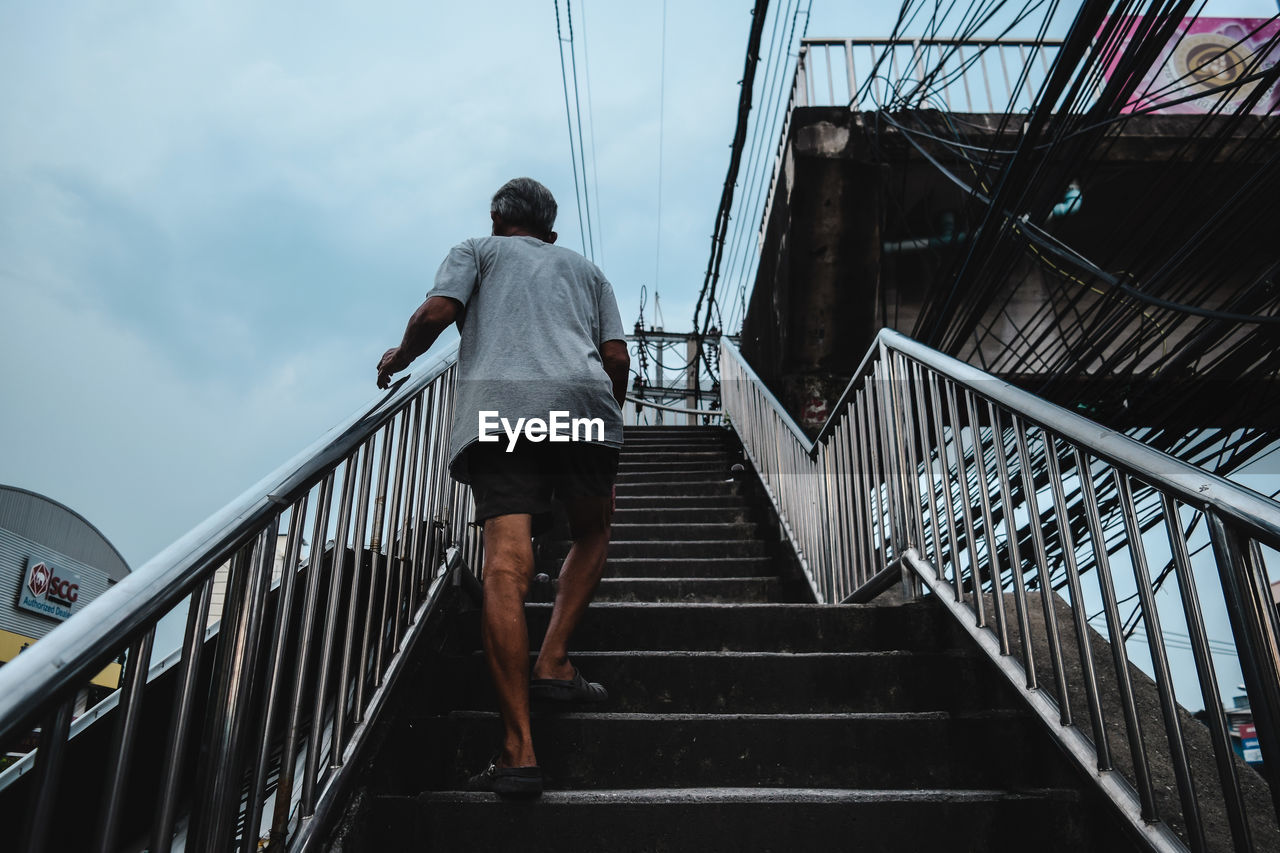 Low angle view of man on staircase against sky