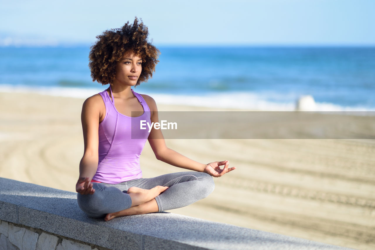 Full length of young woman doing yoga at beach