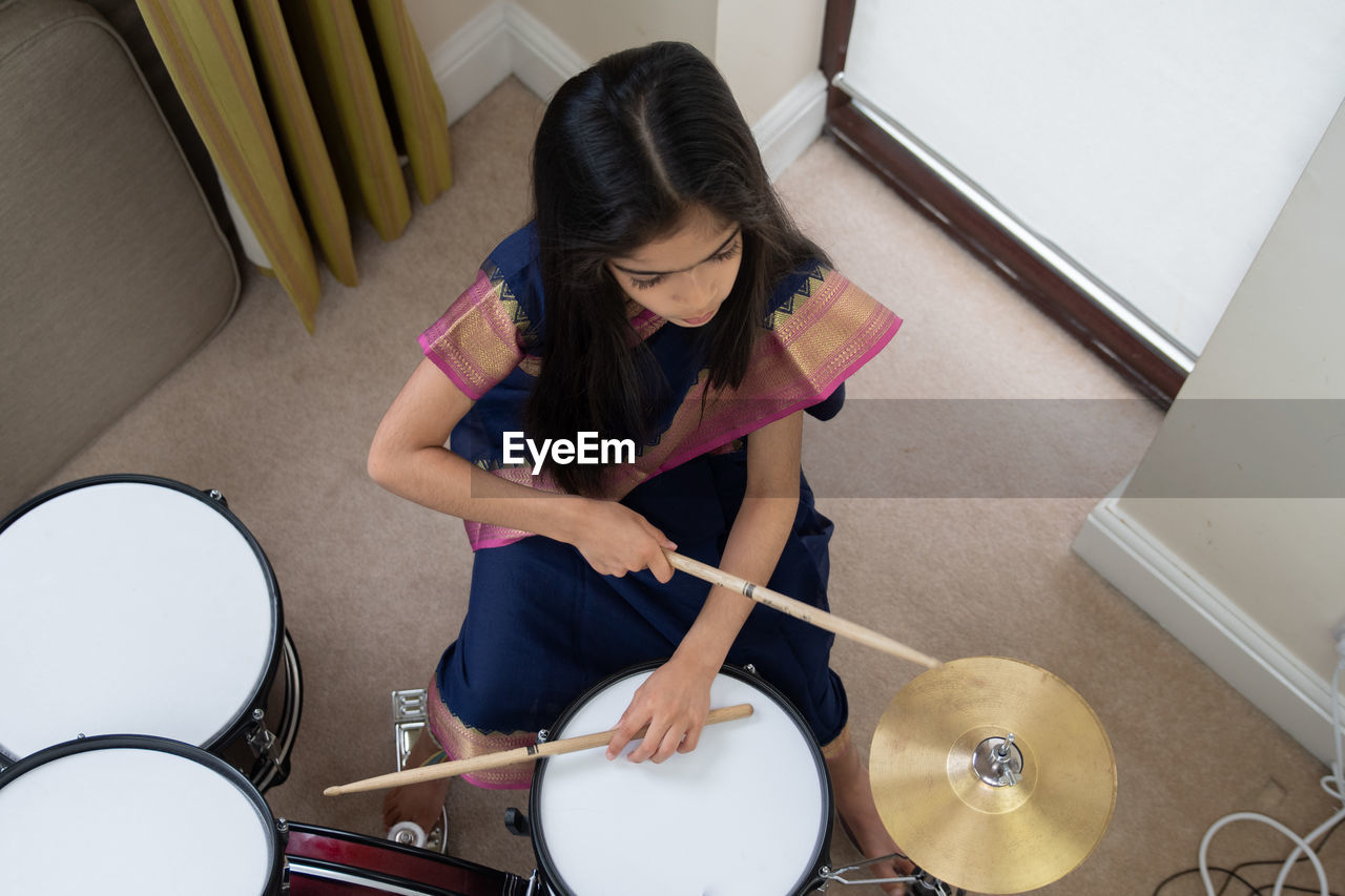 High angle view of girl in sari playing drum