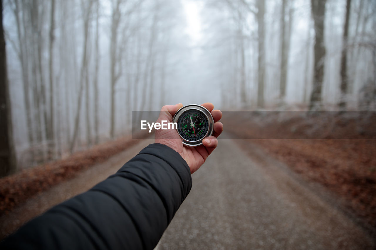 Survival man holding a compass in hand in the foggy forest