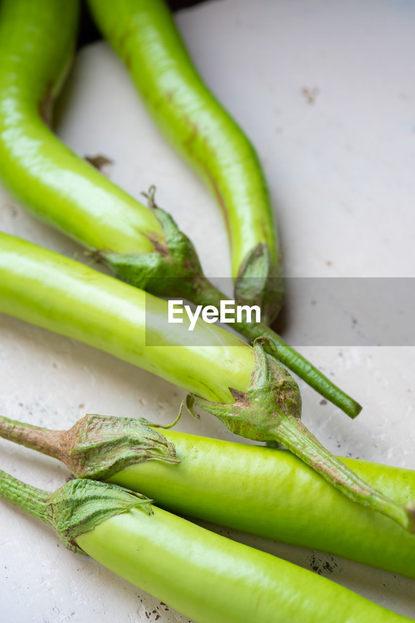 CLOSE-UP OF GREEN CHILI PEPPERS ON TABLE