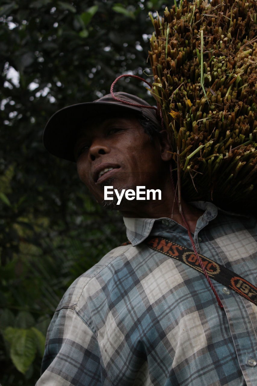 Low angle portrait of farmer carrying crop on shoulder