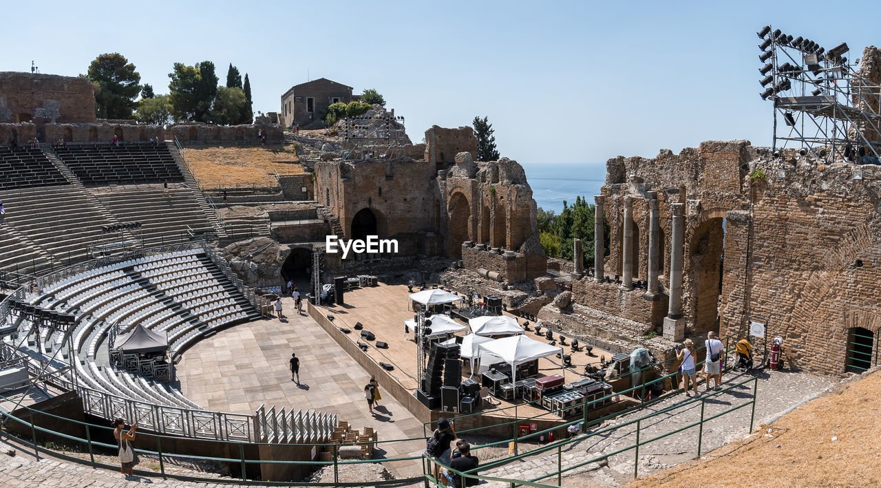 Tourists exploring old ruins of ancient greek theater during summer vacation