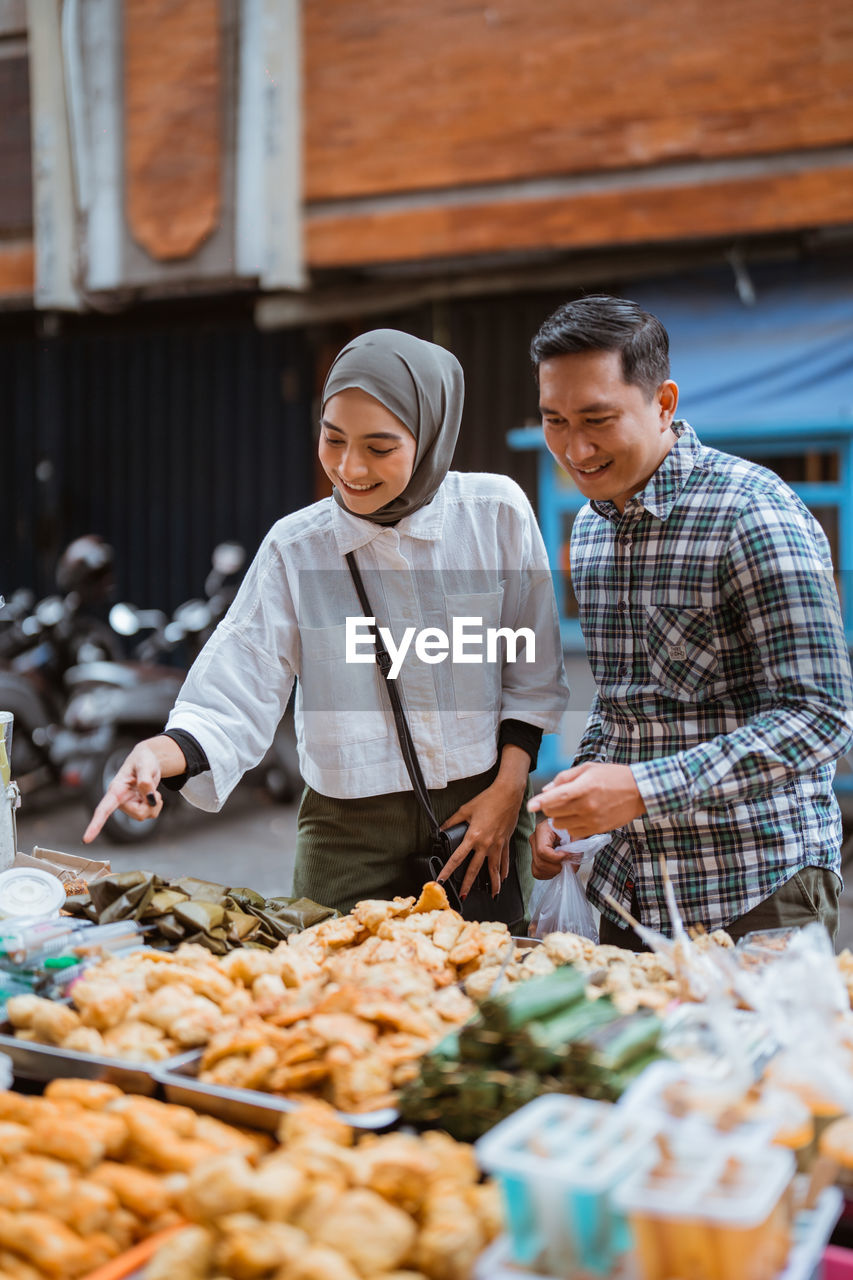 portrait of smiling man holding food at market