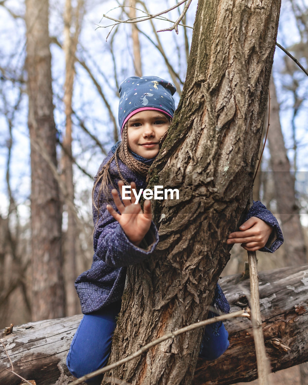 Portrait of girl holding tree trunk