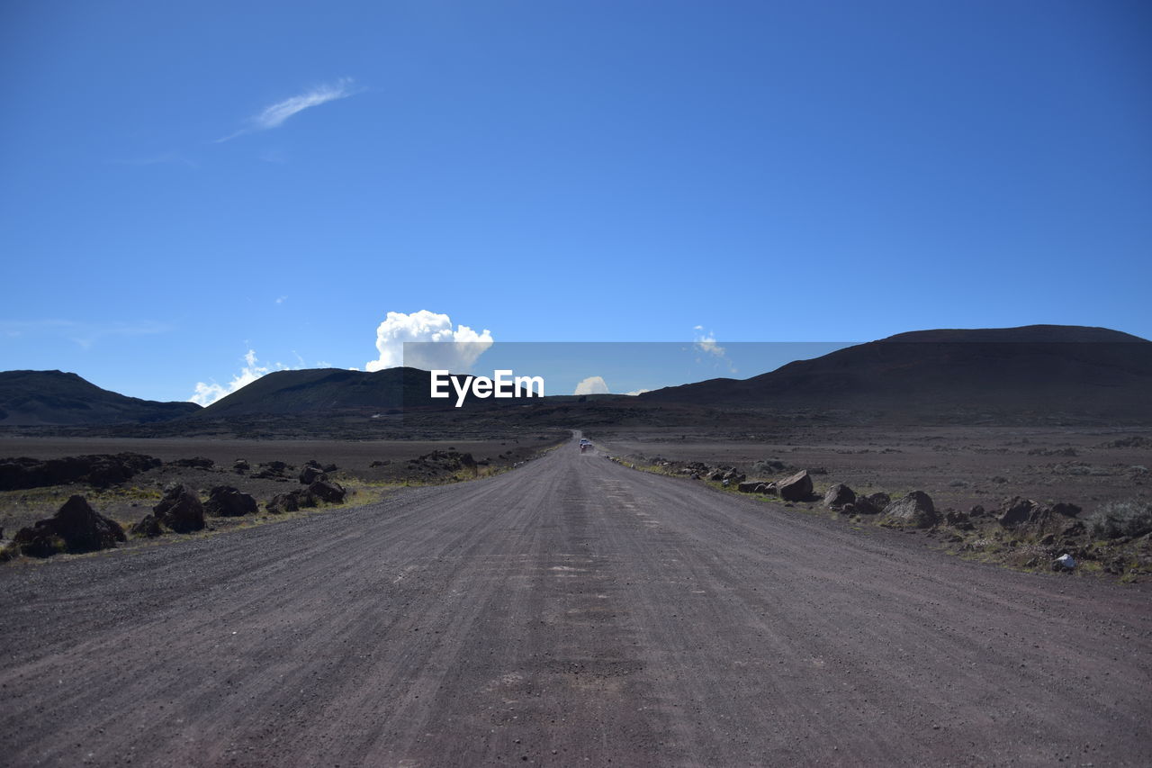 Road amidst desert against blue sky