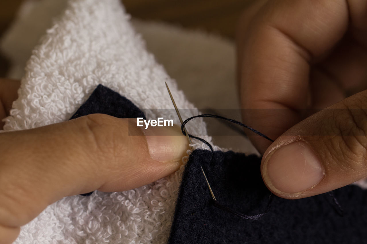 Cropped hands of person stitching textile