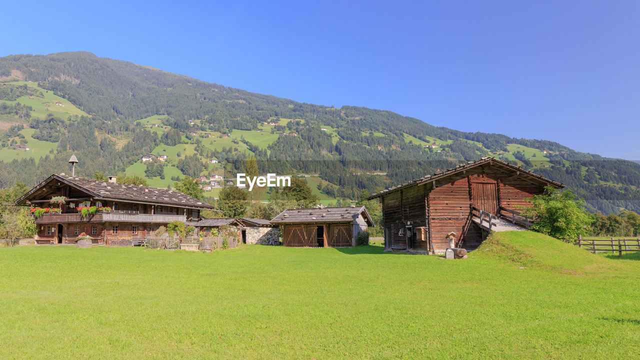 House on field by mountain against sky