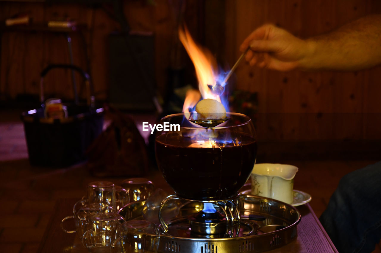 Waiter putting a burning sugarloaf over a bowl of feuerzangenbowle on a restaurant table