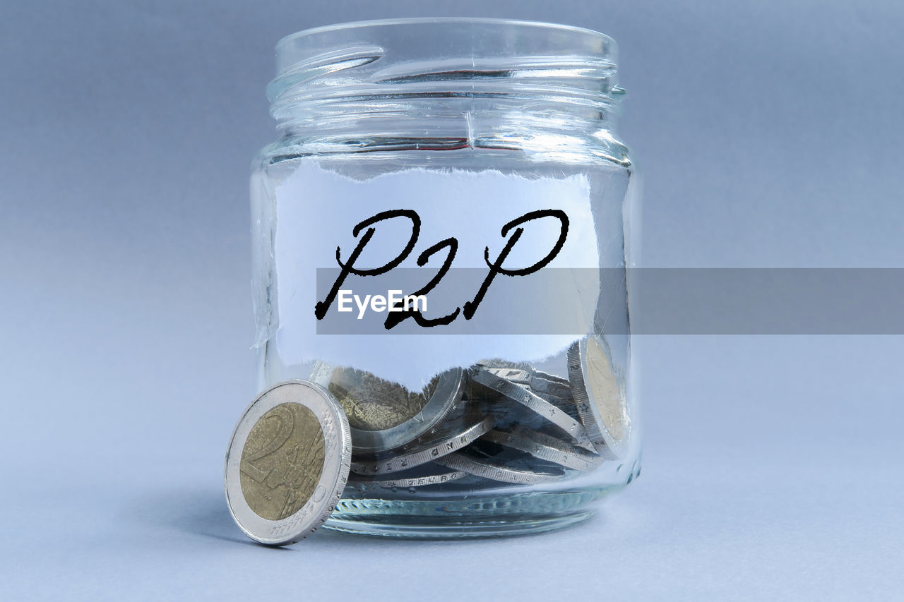 Close-up of coins in jar with text against gray background