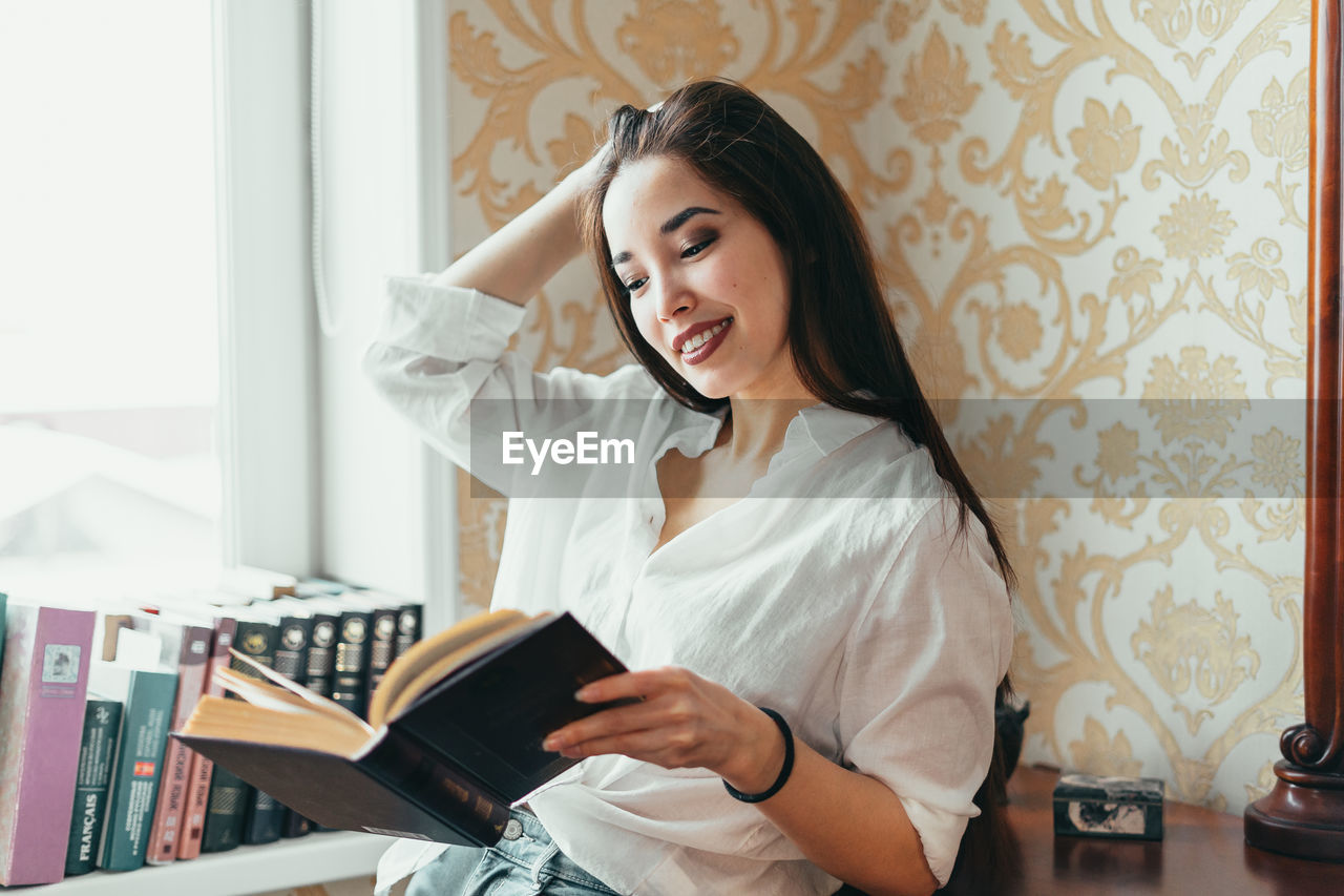 Young woman reading book at home