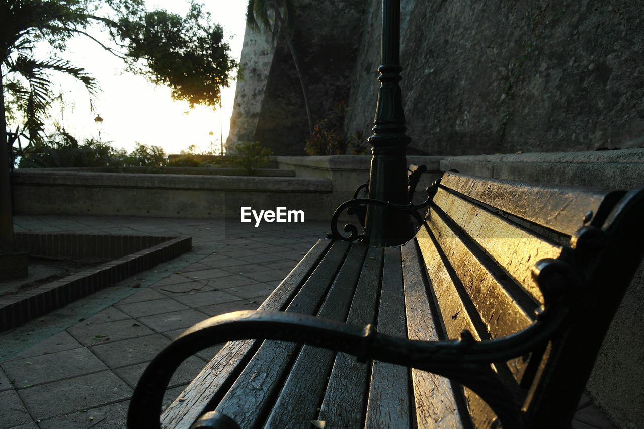 Empty bench by wall at park