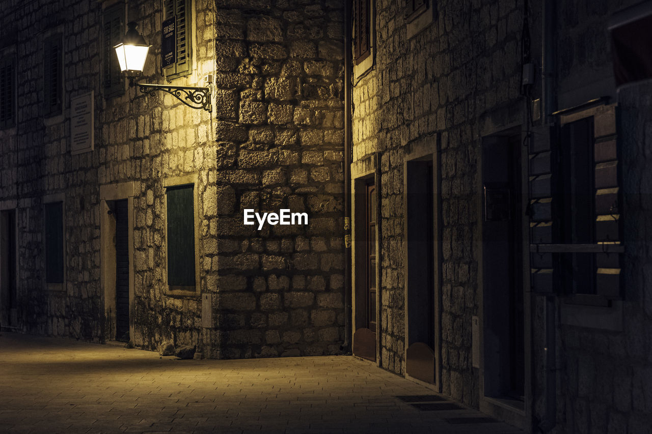 Empty alley amidst buildings in city at night