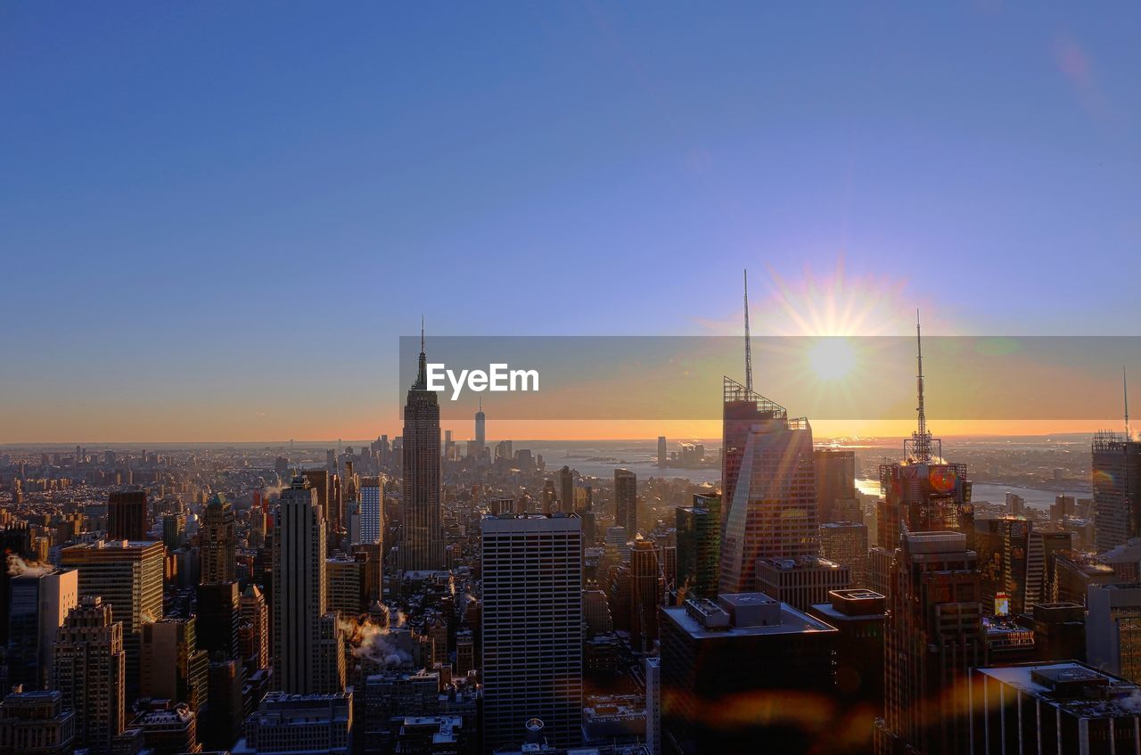 Illuminated cityscape against sky during sunset