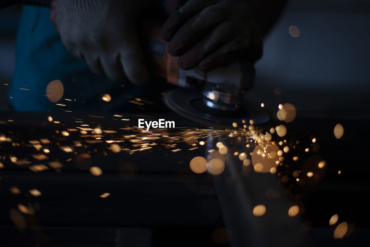 cropped hand of person holding illuminated string lights at night