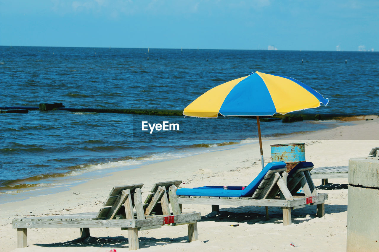 DECK CHAIRS ON BEACH AGAINST SEA