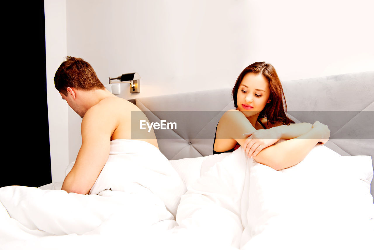Young couple in blanket on bed at home