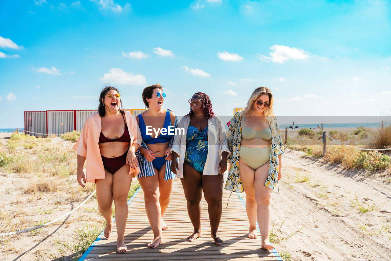 portrait of smiling friends standing on beach