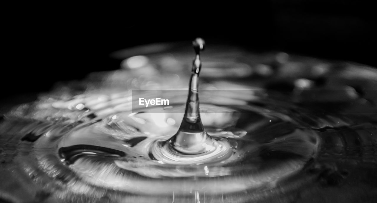 CLOSE-UP OF DROP SPLASHING ON WATER IN BLACK