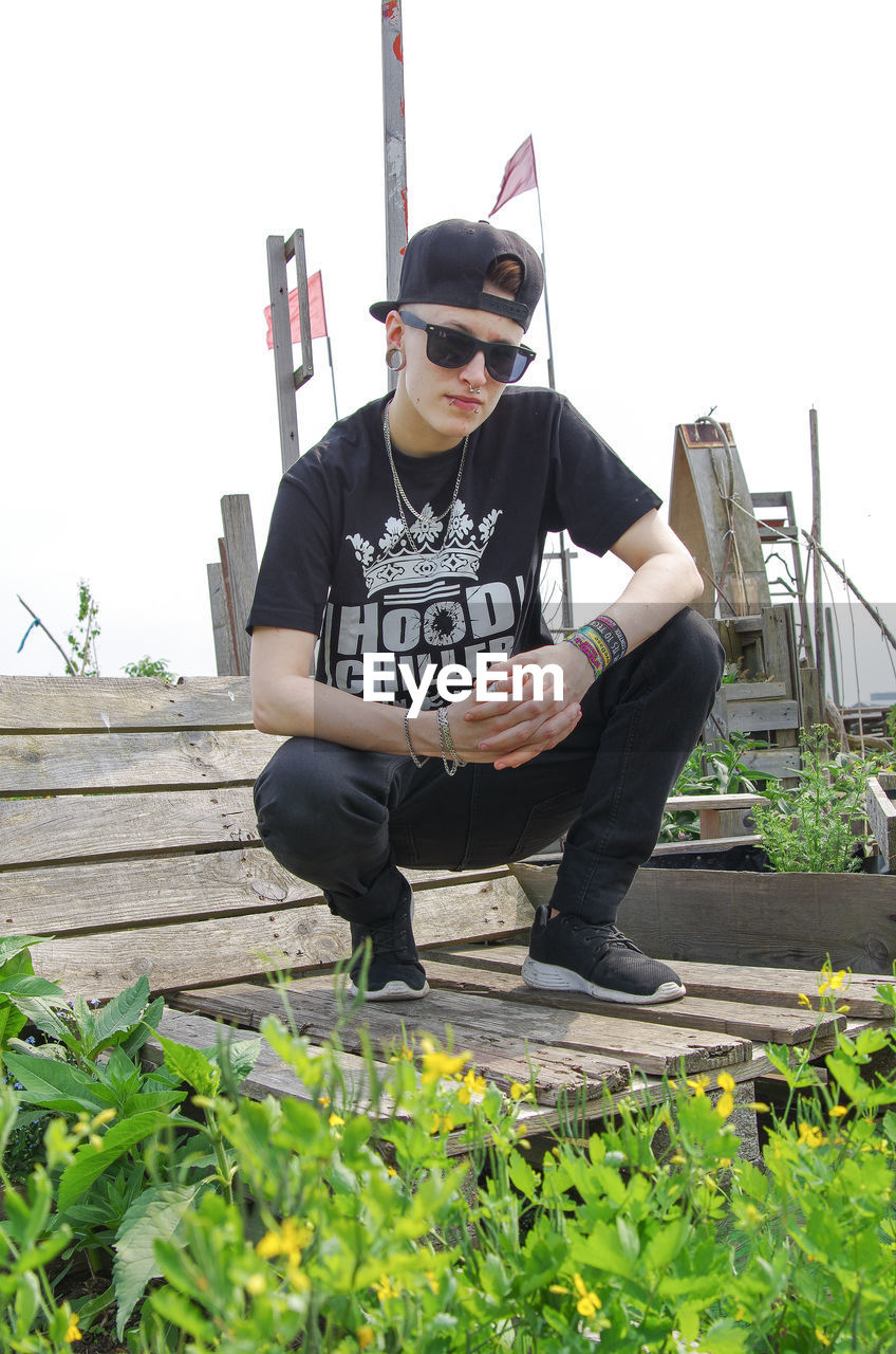 Full length hipster man sitting on bench