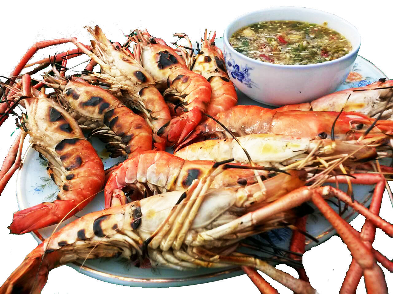 Close-up of roasted tiger prawns served with sauce in plate over white background