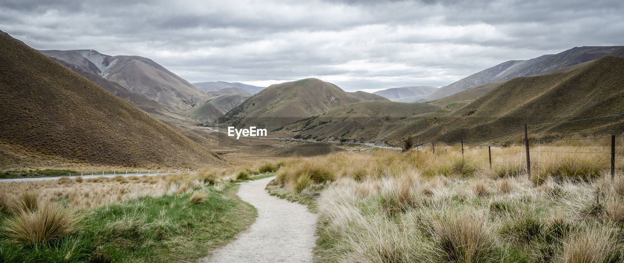 Panorama of dry valley with path leading to the centre of frame. lindis pass, new zealand