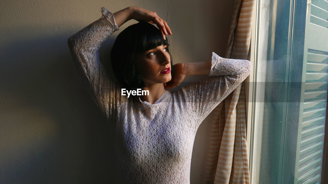 Woman looking through window at home