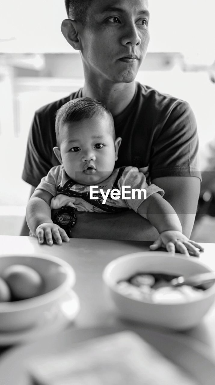 Portrait of son with father by table at home