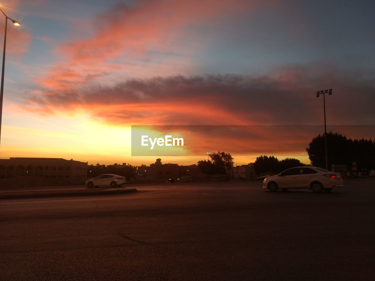 CARS ON ROAD AGAINST ORANGE SKY