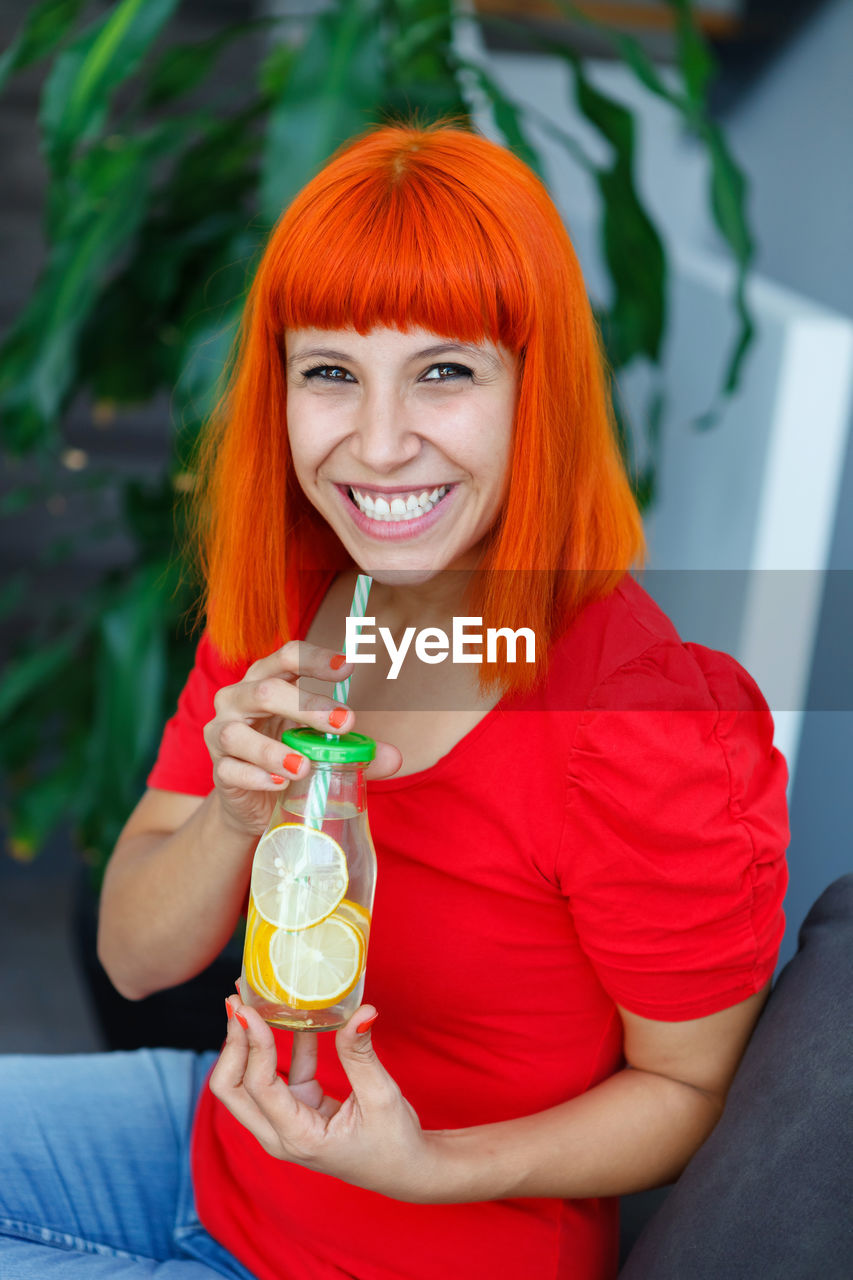 Portrait of smiling young woman drinking drink