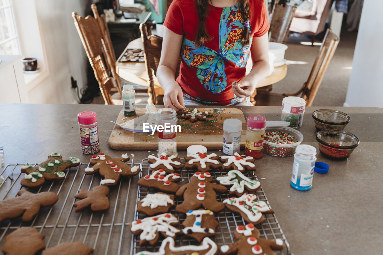 Girls hands putting sprinkles on christmas cookies