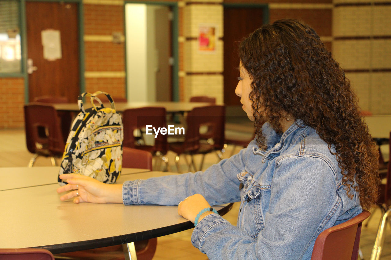 YOUNG WOMAN SITTING BY TABLE AND TABLES