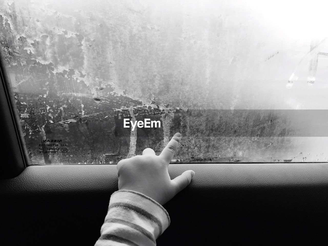 Cropped hand of child touching car window