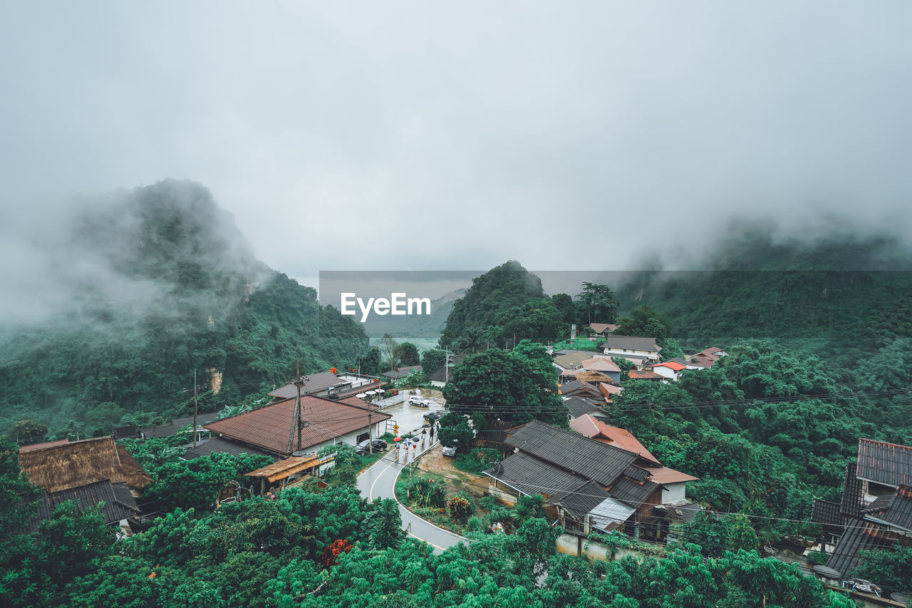 HIGH ANGLE VIEW OF HOUSES AND TREES AGAINST MOUNTAINS