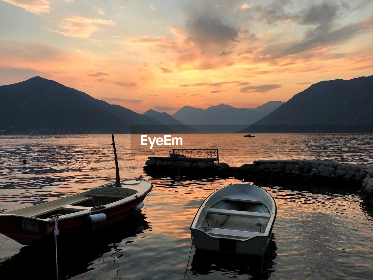 BOAT MOORED ON SEA AGAINST ORANGE SKY