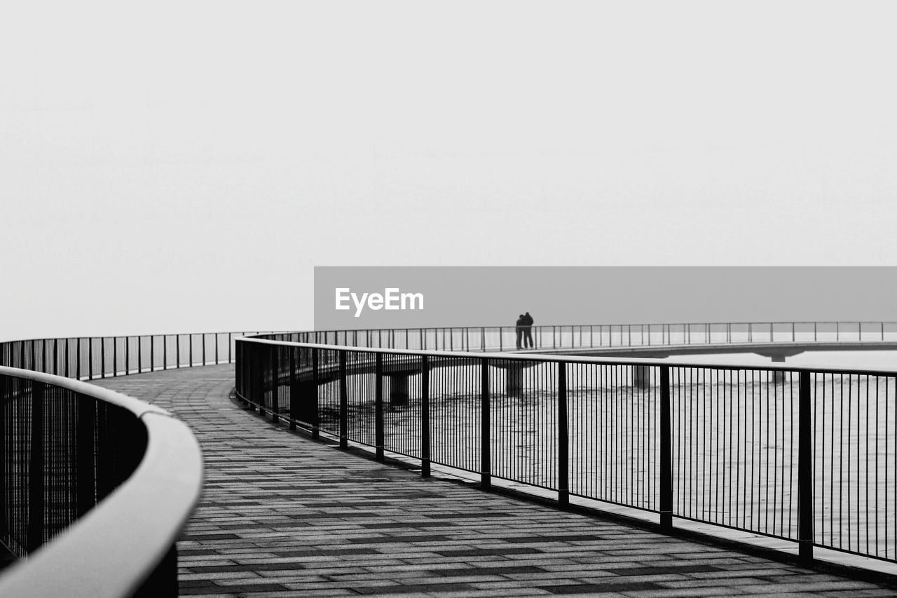 Footbridge over pier against clear sky