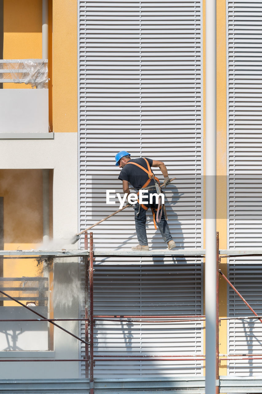 LOW ANGLE VIEW OF MEN WORKING ON BUILDING