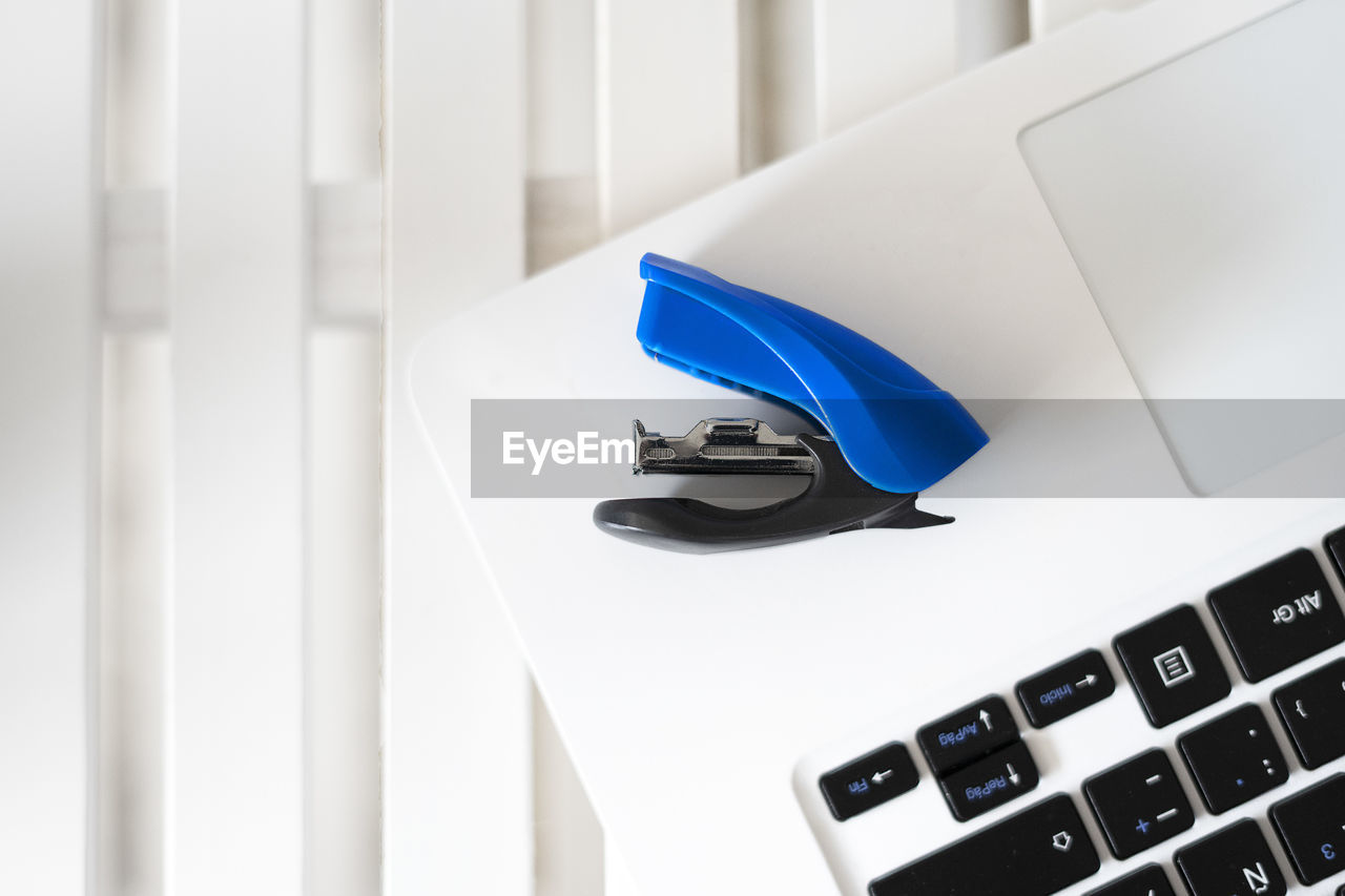 Blue stapler on top of a white laptop.