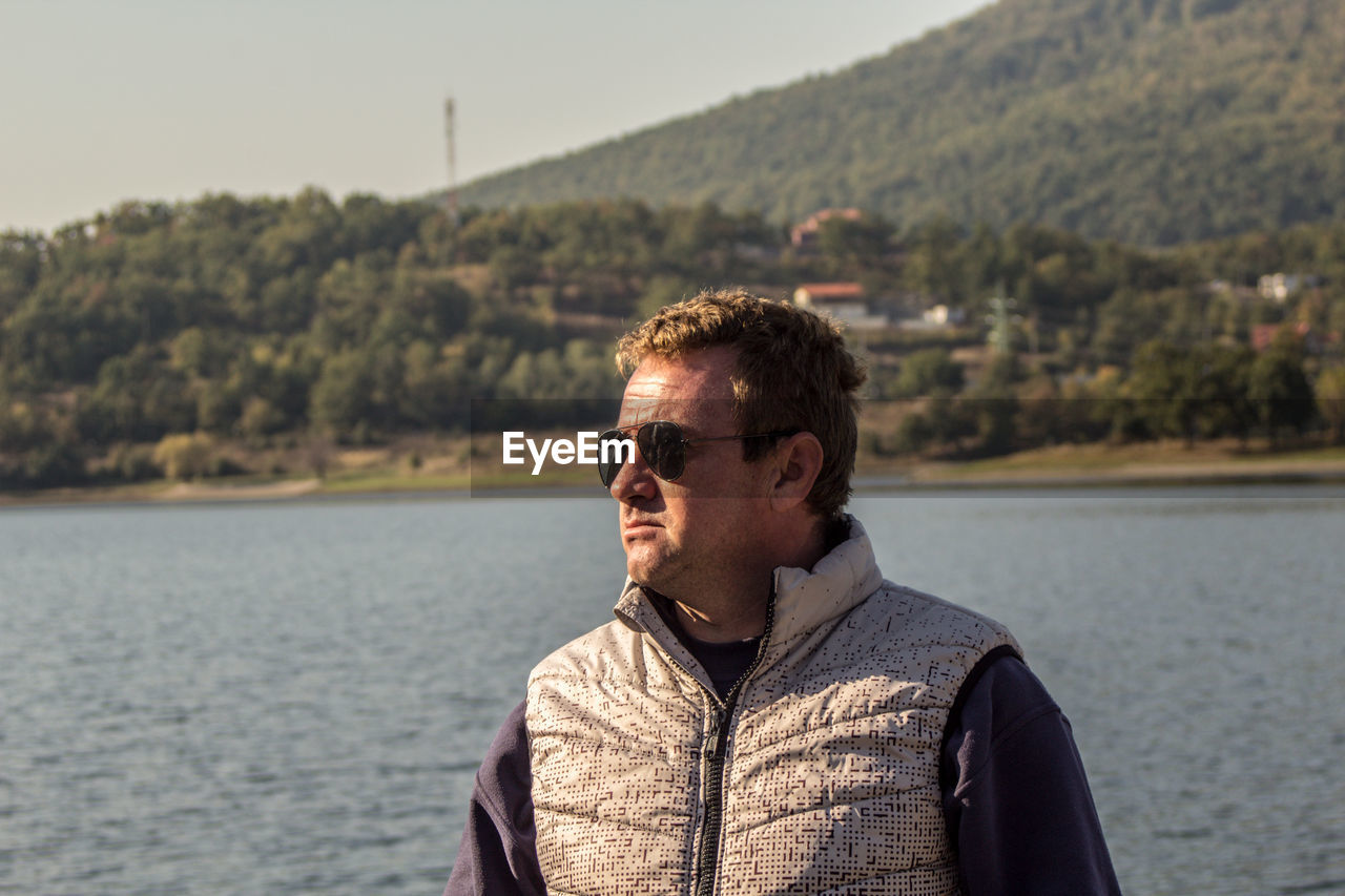 Portrait of young man standing against lake