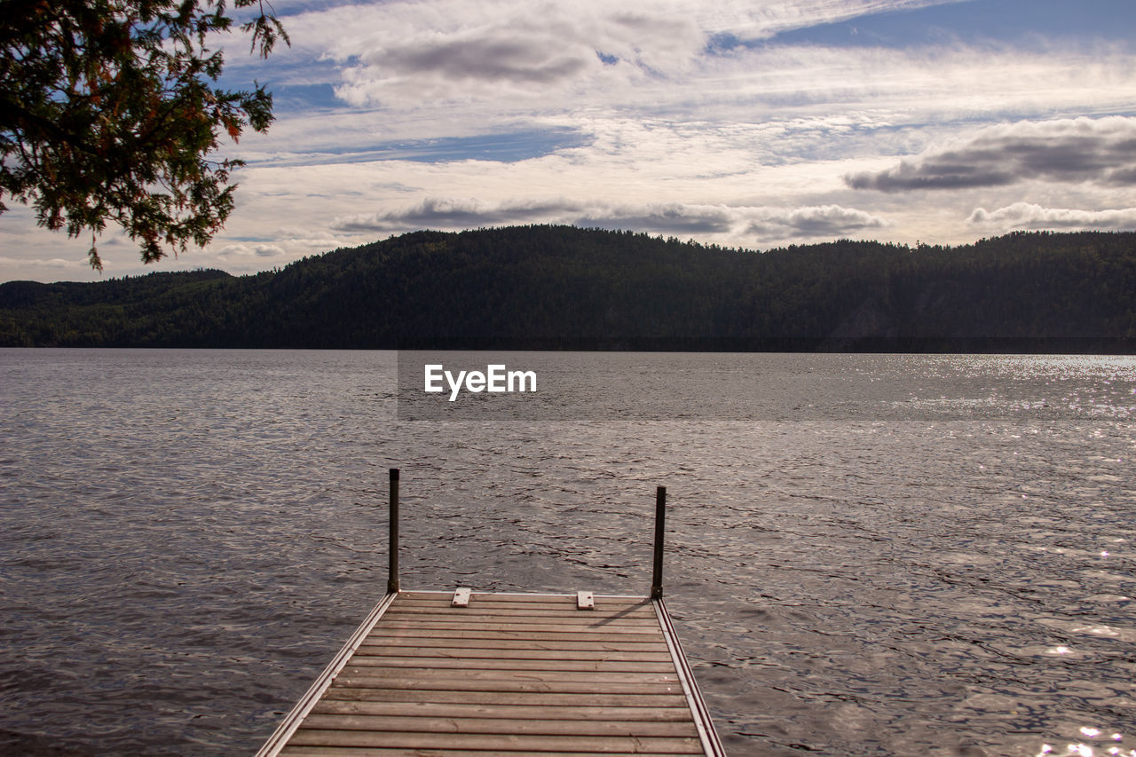 water, sky, scenics - nature, lake, beauty in nature, nature, tranquility, mountain, tranquil scene, shore, cloud, tree, pier, reflection, wood, no people, environment, landscape, body of water, reservoir, jetty, land, non-urban scene, outdoors, plant, morning, day, idyllic, architecture, travel, travel destinations, horizon, mountain range, vacation, trip, sunlight, forest, holiday, beach