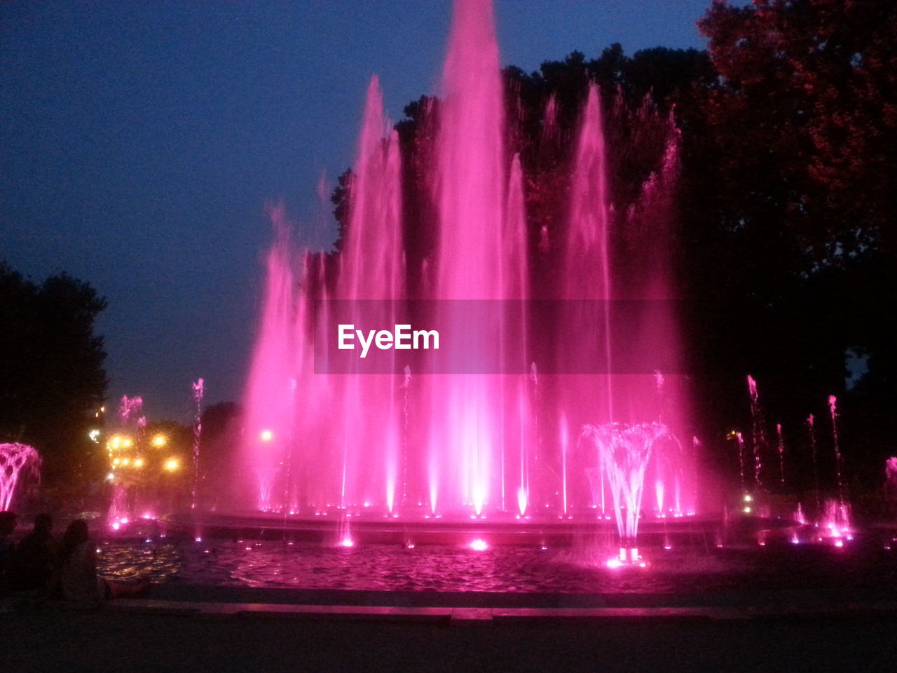 Illuminated fountain in park at dusk