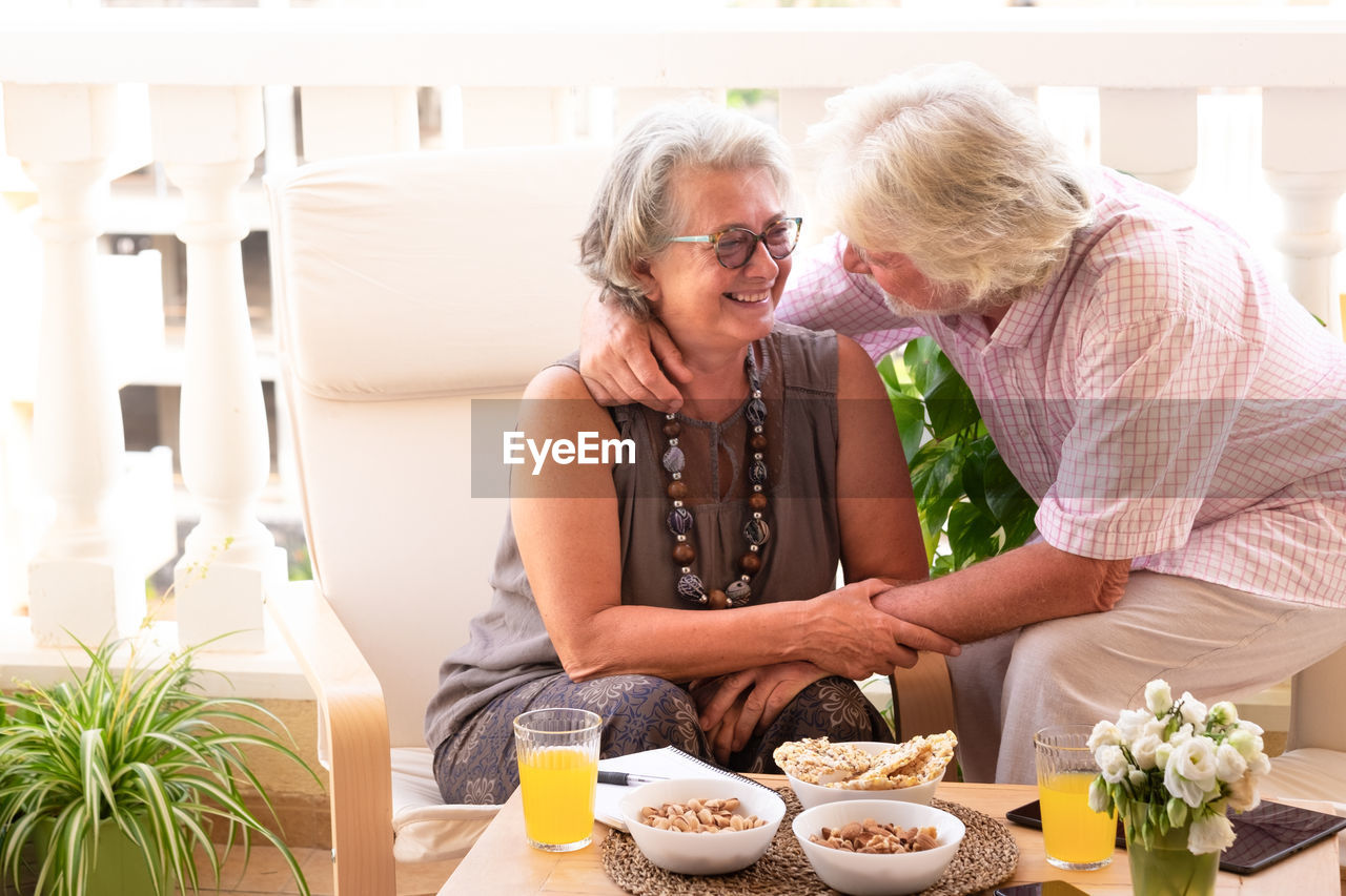 Senior couple embracing while sitting by food on table