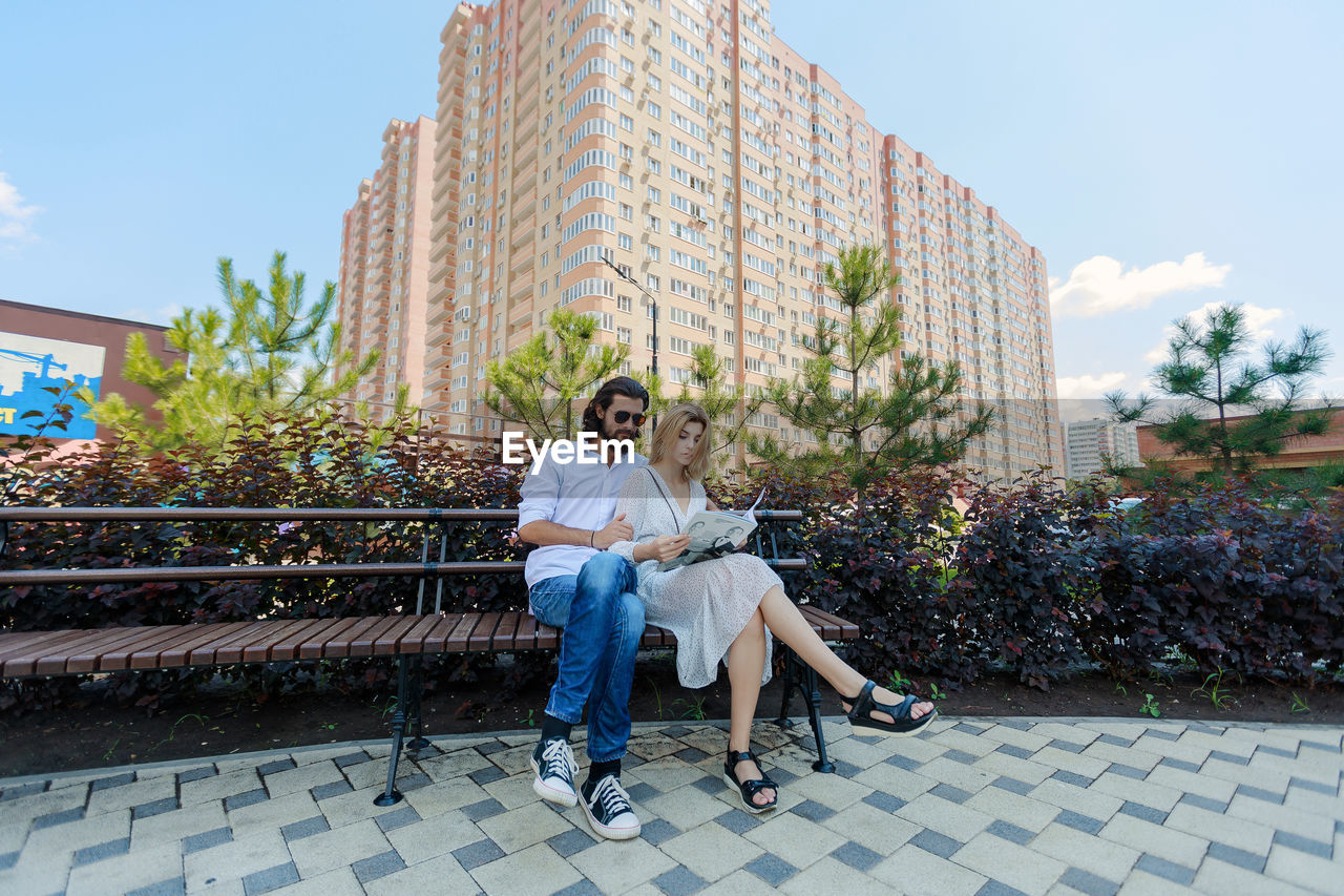 Couple reading newspaper while sitting on bench