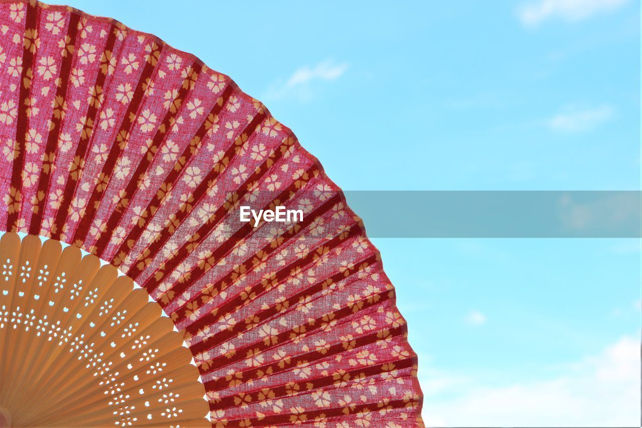 Low angle view of folding fan against blue sky
