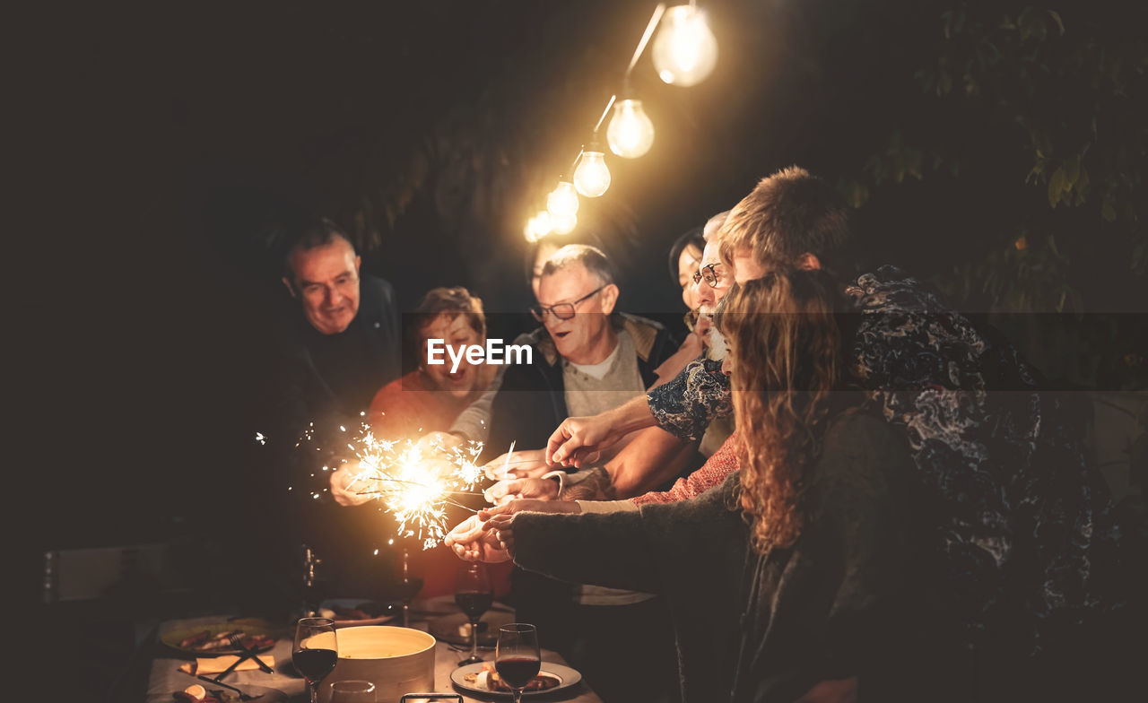 Happy family burning sparklers in yard at night