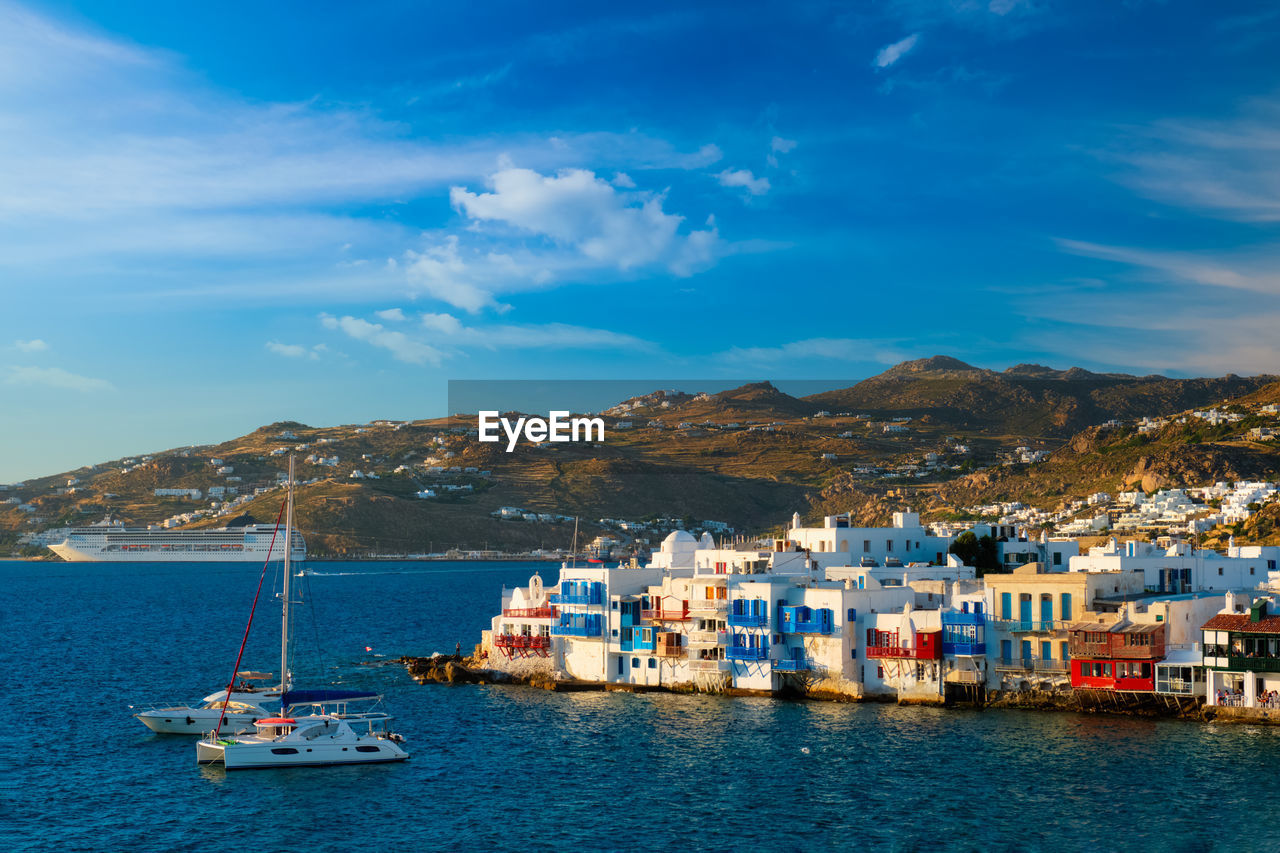 Sunset in mykonos, greece, with cruise ship and yachts in the harbor