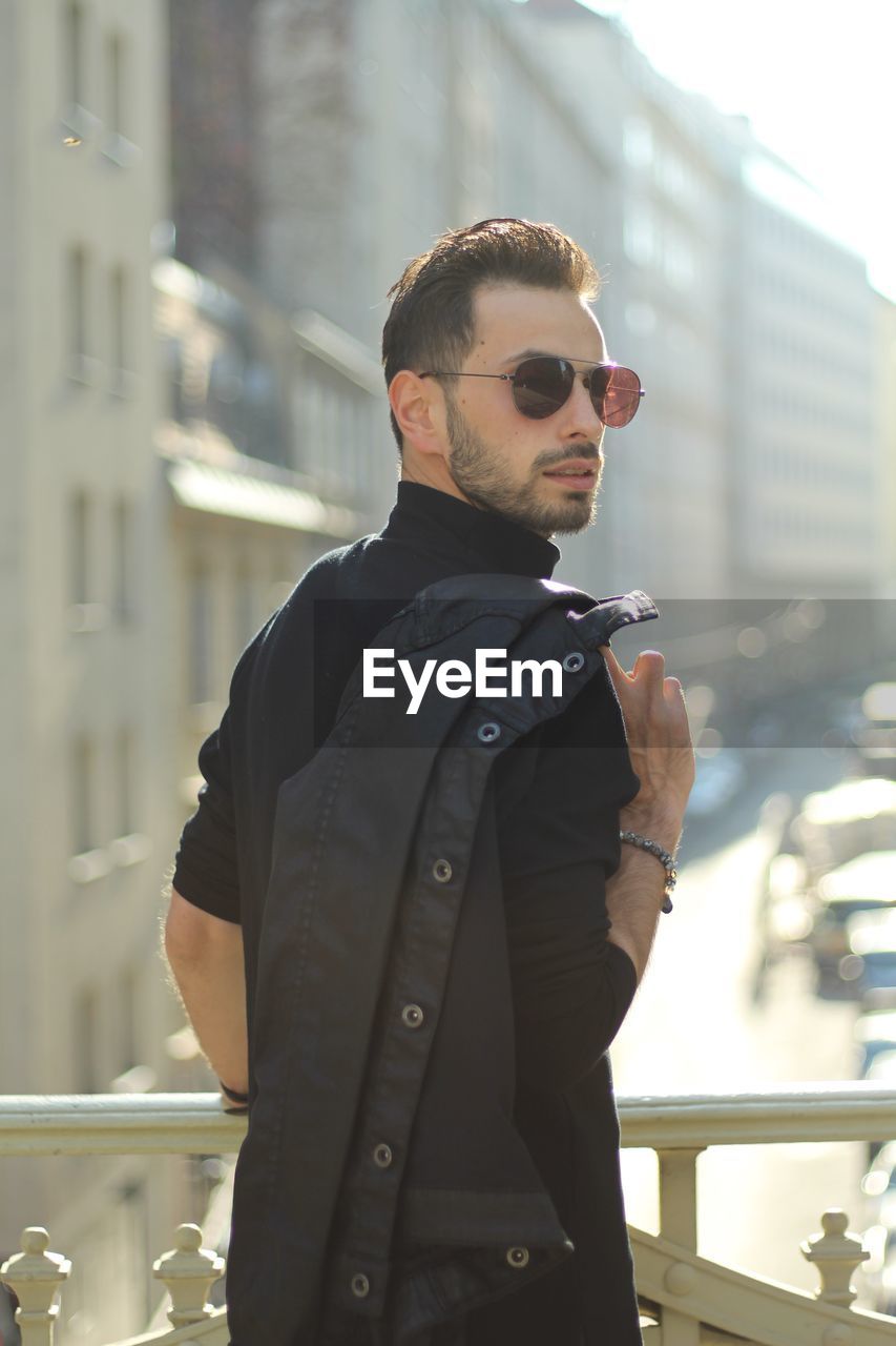 Handsome man wearing sunglasses while standing in city