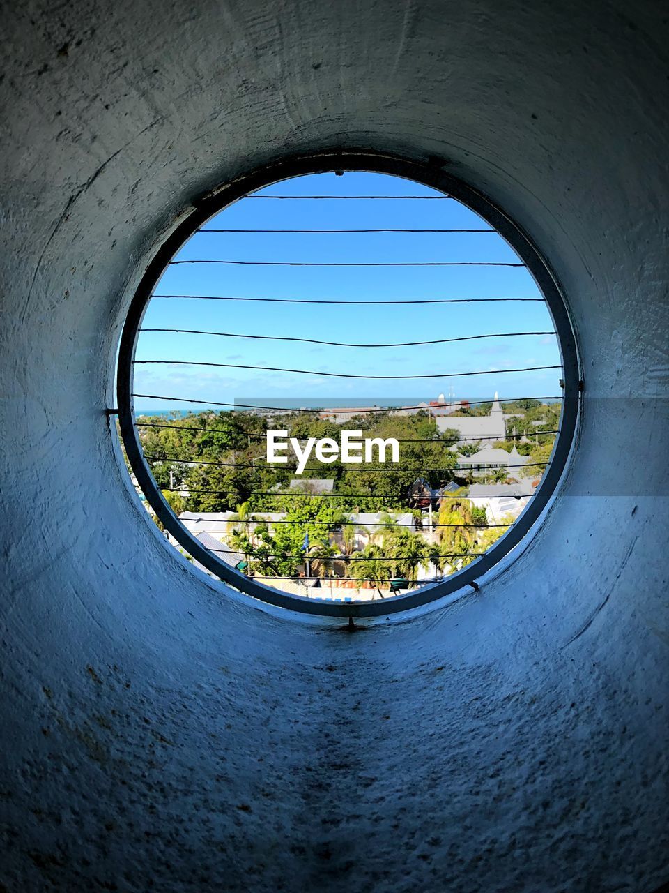 Trees and houses seen through window in wall