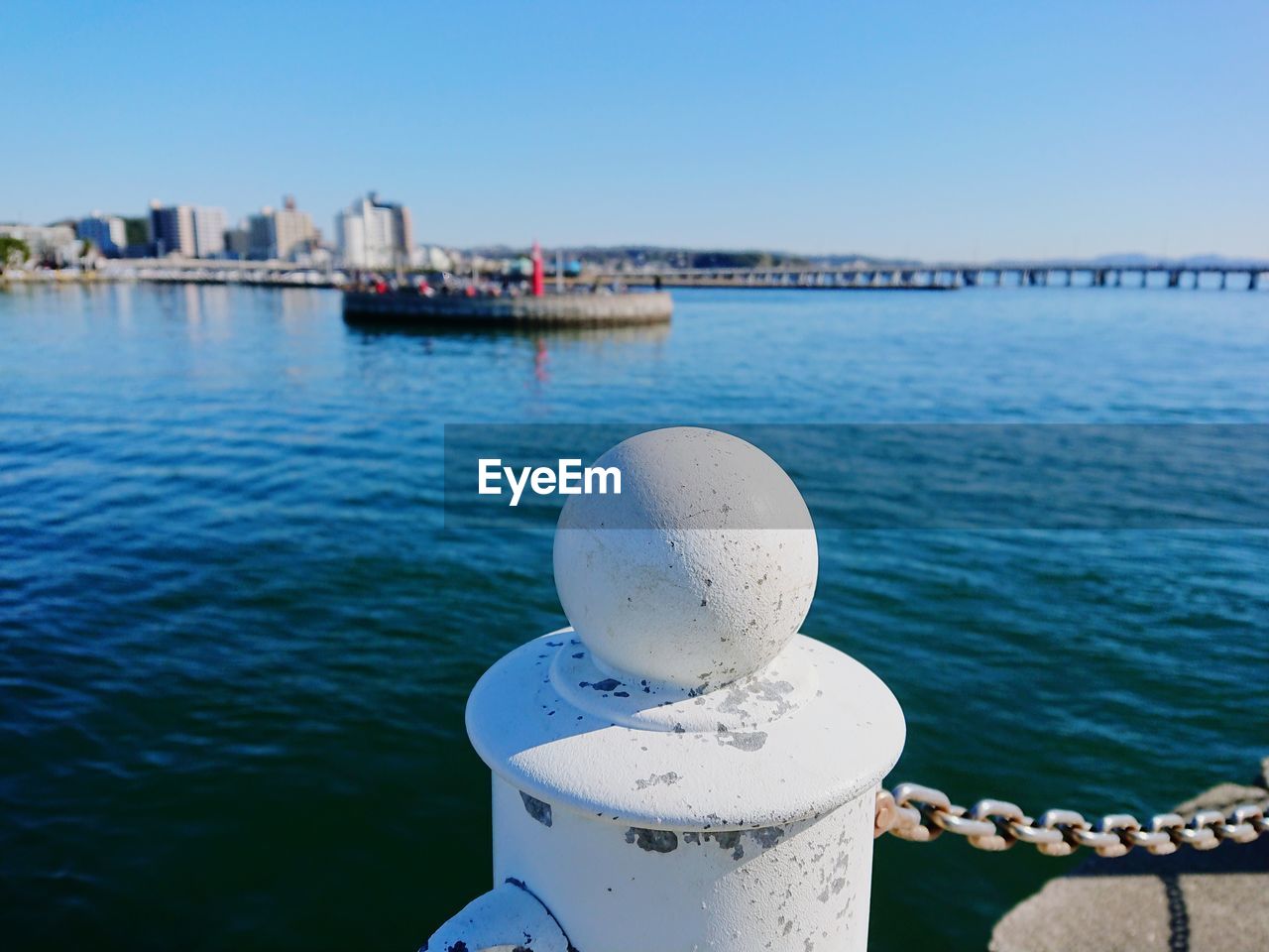 Close-up of metal post in sea against clear sky