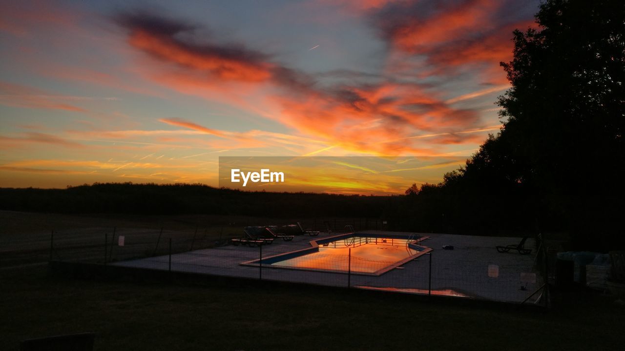 VIEW OF CALM LAKE AGAINST SUNSET SKY